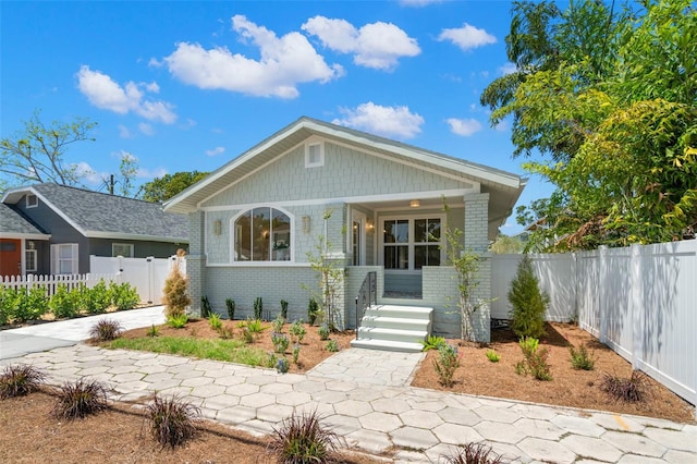 bungalow-style home featuring brick siding, a porch, and fence private yard