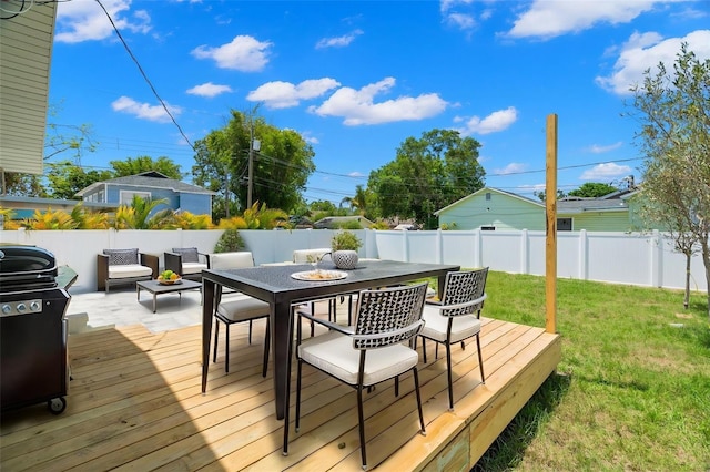 deck with grilling area, a yard, outdoor dining area, and a fenced backyard