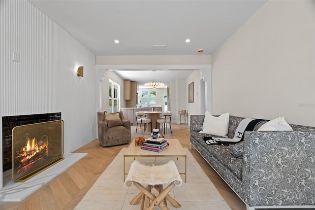living room featuring a warm lit fireplace, recessed lighting, a notable chandelier, and visible vents