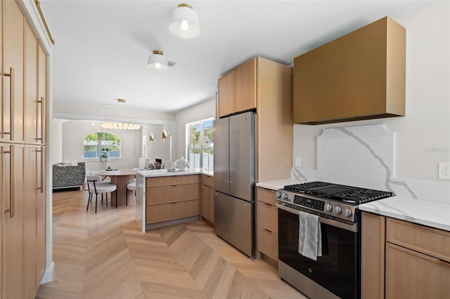 kitchen featuring light stone countertops, decorative light fixtures, a peninsula, and appliances with stainless steel finishes