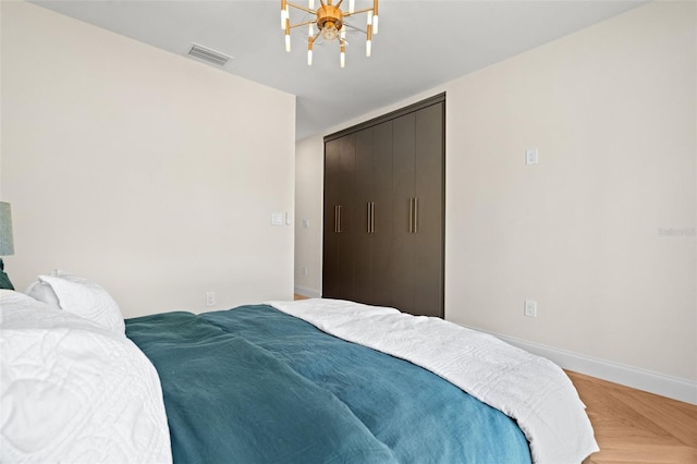 bedroom featuring a closet, visible vents, a chandelier, and baseboards