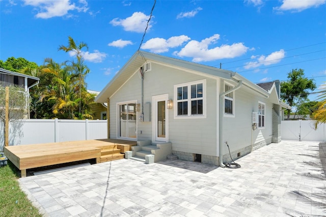 rear view of property featuring fence, a gate, a patio area, and a wooden deck