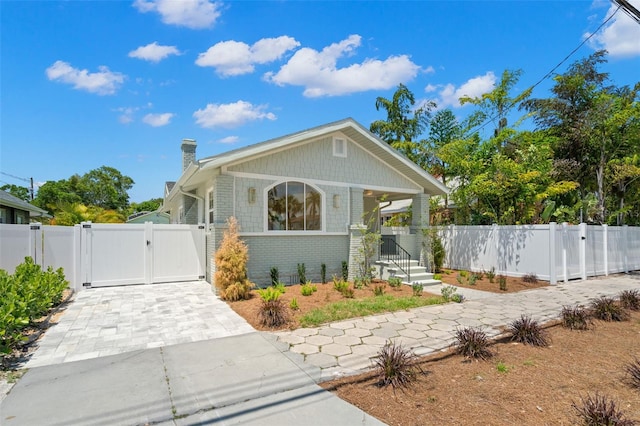 bungalow with brick siding, a chimney, fence private yard, and a gate