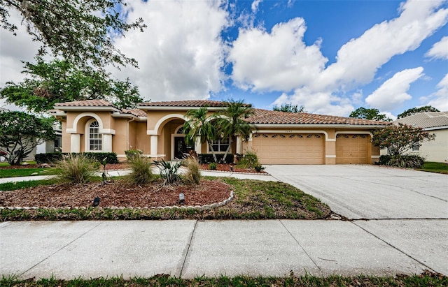 2042 Diamond Ct, Oldsmar, FL 34677 - mediterranean / spanish house with stucco siding, an attached garage, concrete driveway, and a tiled roof
