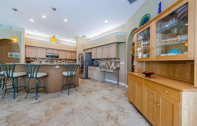 2042 Diamond Ct, Oldsmar, FL 34677 - kitchen with a breakfast bar area, arched walkways, backsplash, and appliances with stainless steel finishes