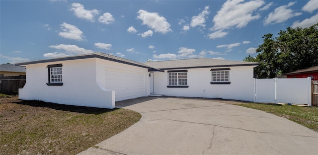 ranch-style home featuring fence, a garage, driveway, and stucco siding