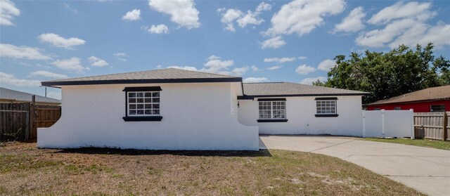 exterior space with stucco siding, fence, a yard, and concrete driveway