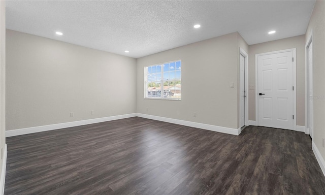 spare room featuring recessed lighting, a textured ceiling, dark wood-style flooring, and baseboards