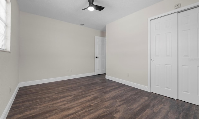 unfurnished bedroom featuring baseboards, dark wood finished floors, visible vents, and a closet