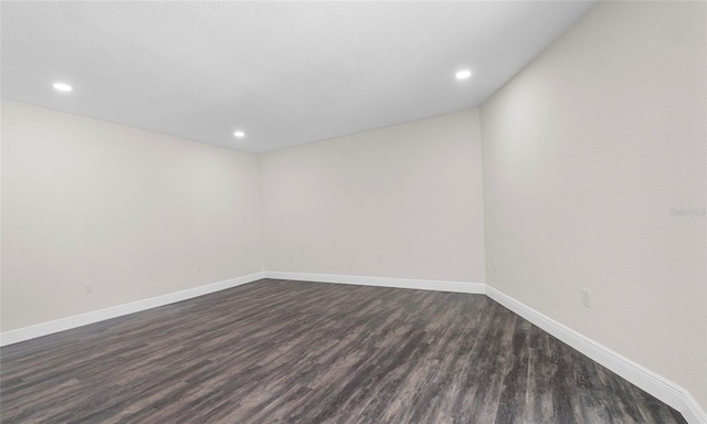 empty room with recessed lighting, baseboards, and dark wood-style floors