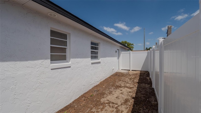 view of side of property featuring stucco siding and fence