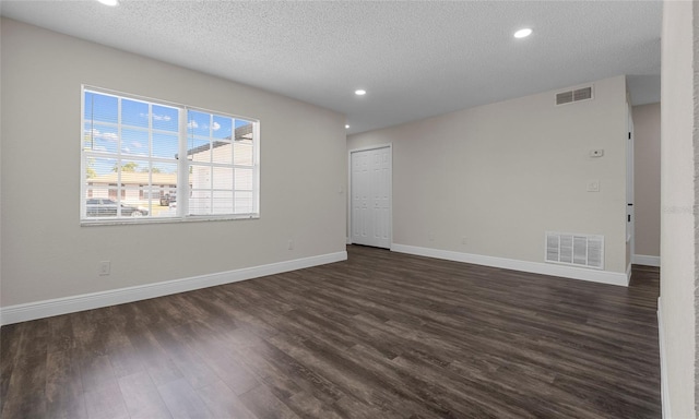 empty room with baseboards, dark wood finished floors, and visible vents