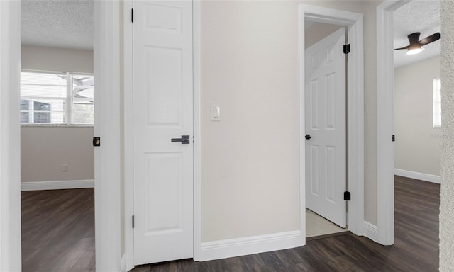 hall with baseboards, a textured ceiling, and dark wood-style flooring