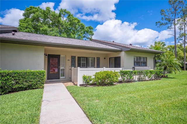ranch-style home with covered porch, a front yard, and stucco siding