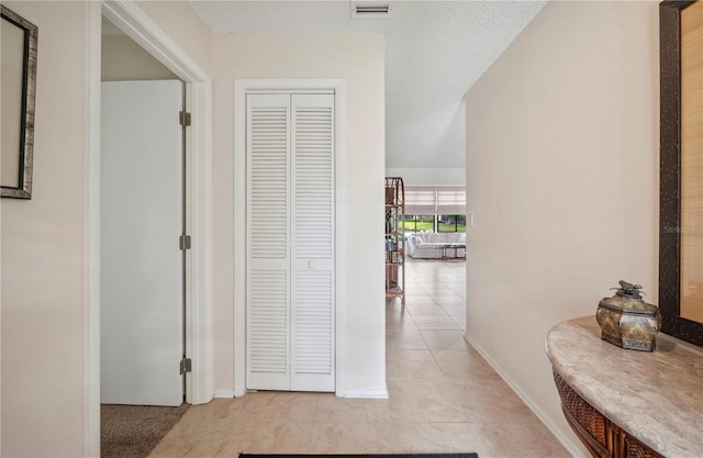 hall featuring visible vents, baseboards, and light tile patterned floors