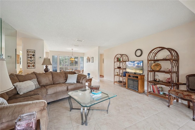 living room with a textured ceiling, visible vents, and light tile patterned floors