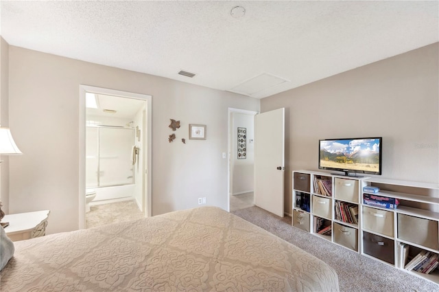 carpeted bedroom featuring ensuite bath, a textured ceiling, visible vents, and attic access