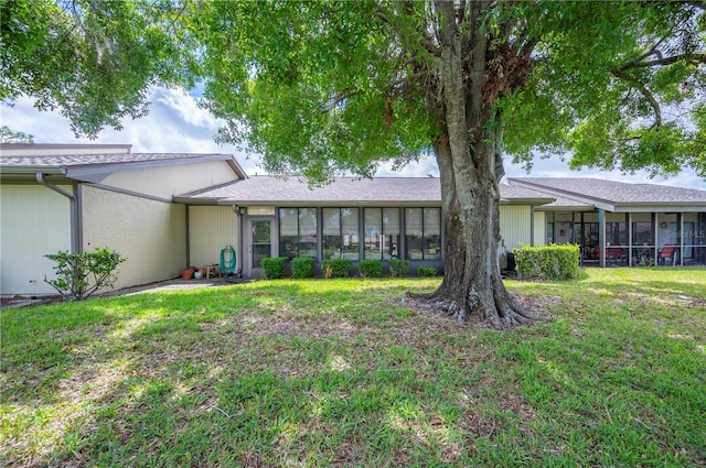 back of property with a sunroom and a yard