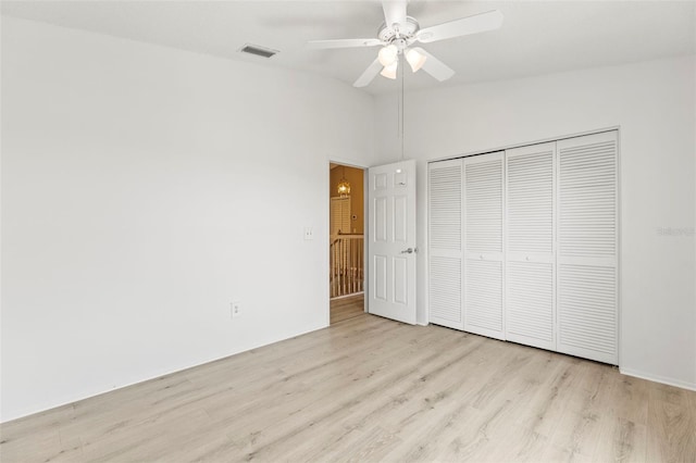 unfurnished bedroom with ceiling fan, visible vents, vaulted ceiling, light wood-type flooring, and a closet