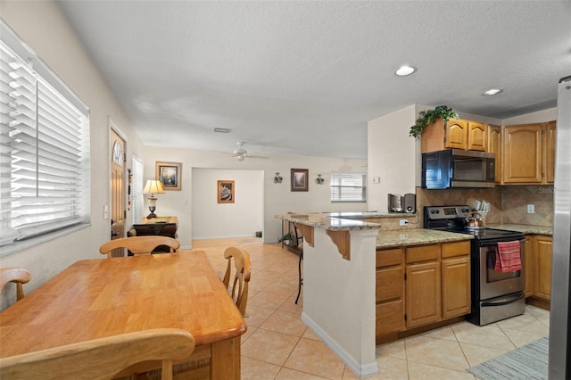 2903 W Paxton Ave, Tampa, FL 33611 - kitchen with electric range, light tile patterned floors, a peninsula, backsplash, and light stone counters