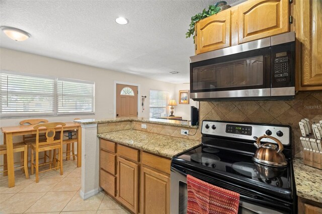 2903 W Paxton Ave, Tampa, FL 33611 - kitchen featuring stainless steel appliances, a peninsula, plenty of natural light, tasteful backsplash, and a textured ceiling