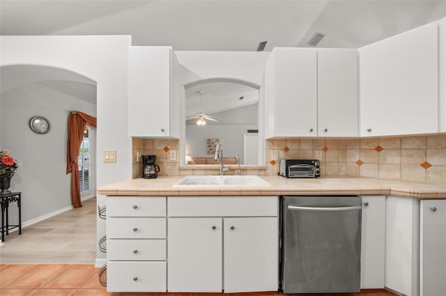 6917 Spumoni St, Sebring, FL 33872 - kitchen featuring dishwasher, a sink, lofted ceiling, arched walkways, and white cabinetry