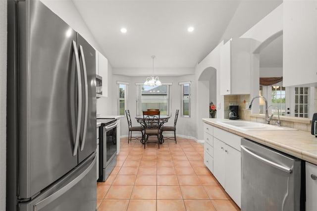 6917 Spumoni St, Sebring, FL 33872 - kitchen featuring appliances with stainless steel finishes, a sink, white cabinets, recessed lighting, and tile countertops