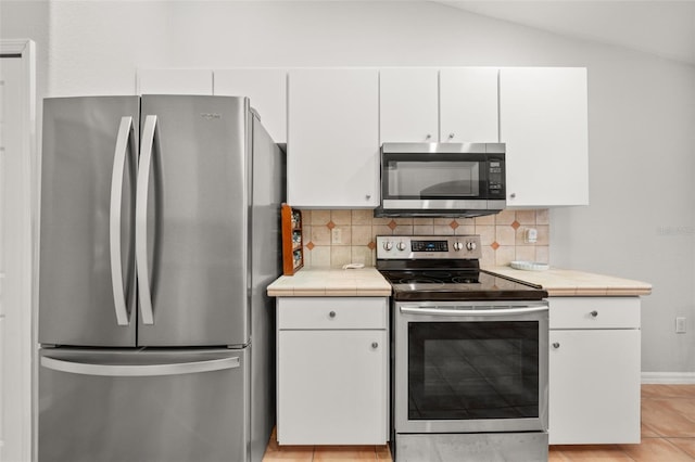 6917 Spumoni St, Sebring, FL 33872 - kitchen featuring stainless steel appliances, tile counters, decorative backsplash, white cabinets, and vaulted ceiling