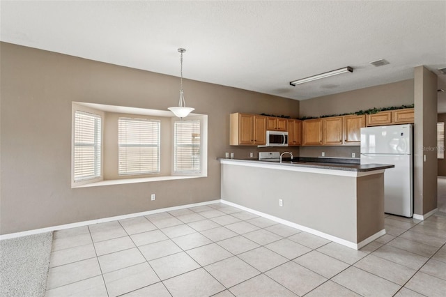 20606 Whitewood Way, Tampa, FL 33647 - kitchen featuring freestanding refrigerator, a peninsula, decorative light fixtures, and baseboards