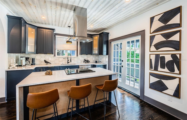 2536 Burlington Ave N, Saint Petersburg, FL 33713 - kitchen with light countertops, a kitchen breakfast bar, black electric cooktop, backsplash, and glass insert cabinets