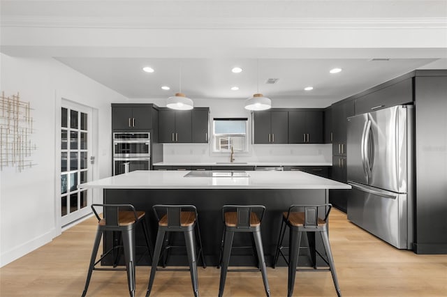 17730 Long Point Dr, Redington Shores, FL 33708 - kitchen featuring a center island, dark cabinetry, light countertops, a kitchen bar, and appliances with stainless steel finishes