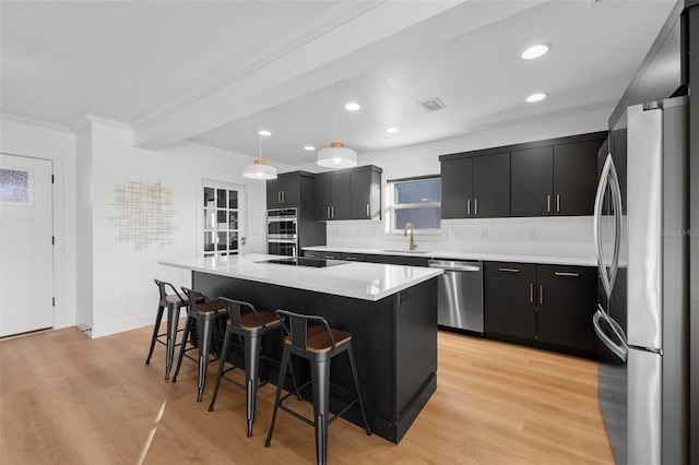 17730 Long Point Dr, Redington Shores, FL 33708 - kitchen featuring a kitchen breakfast bar, visible vents, dark cabinetry, crown molding, and appliances with stainless steel finishes