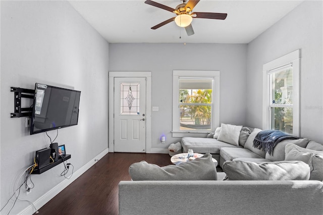 living room featuring dark wood-type flooring, a ceiling fan, baseboards, and plenty of natural light