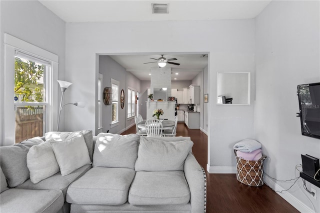 living room featuring baseboards, visible vents, ceiling fan, and dark wood-type flooring