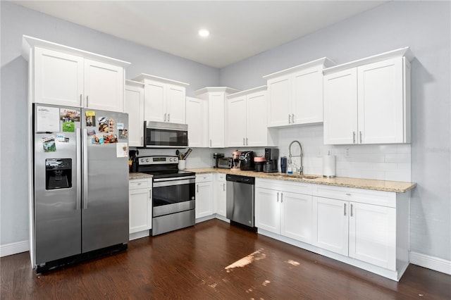 kitchen featuring white cabinets, a sink, stainless steel appliances, baseboards, and dark wood-type flooring