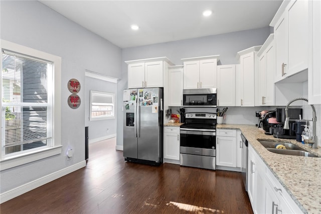 kitchen featuring white cabinetry, light stone counters, appliances with stainless steel finishes, and a sink