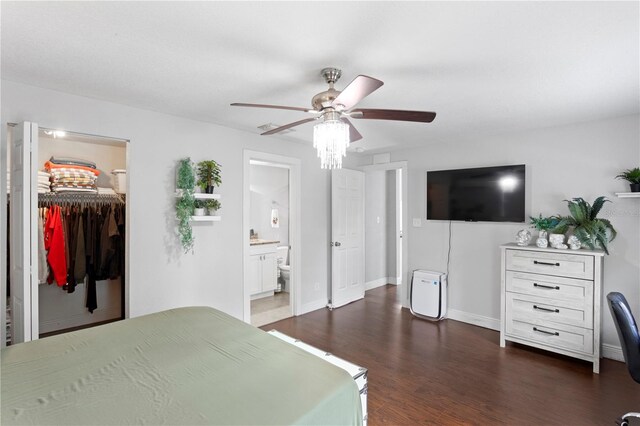 bedroom with baseboards, a closet, a walk in closet, a ceiling fan, and dark wood-type flooring