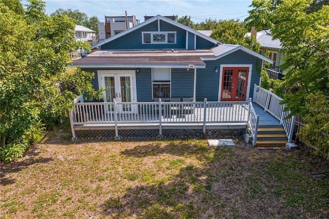 view of front facade featuring a front lawn, a wooden deck, and french doors