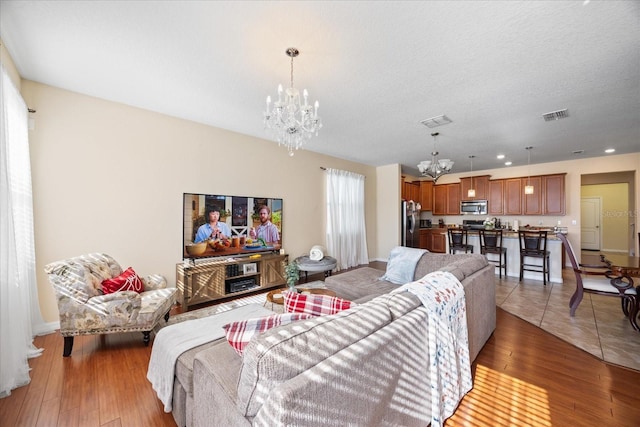 1227 Ballard Green Pl, Brandon, FL 33511 - living room featuring visible vents, light wood finished floors, baseboards, and an inviting chandelier