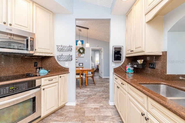 2435 Comerwood Dr, Spring Hill, FL 34609 - kitchen featuring lofted ceiling, stainless steel appliances, dark stone countertops, backsplash, and a sink