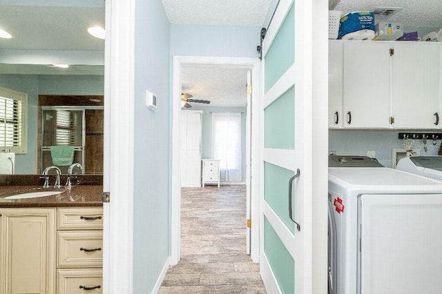 2435 Comerwood Dr, Spring Hill, FL 34609 - clothes washing area with washer and clothes dryer, a sink, a textured ceiling, ceiling fan, and cabinet space