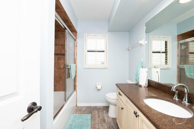 2435 Comerwood Dr, Spring Hill, FL 34609 - bathroom with bath / shower combo with glass door, toilet, baseboards, wood finished floors, and vanity