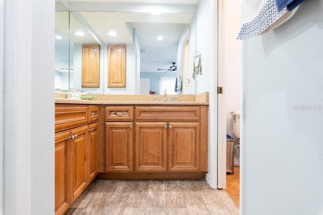 2435 Comerwood Dr, Spring Hill, FL 34609 - bathroom with wood finished floors, a sink, ceiling fan, double vanity, and recessed lighting