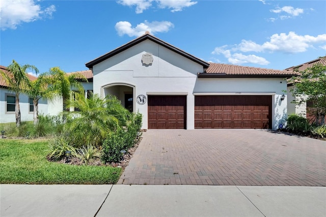 17583 Holly Well Ave, Wimauma, FL 33598 - view of front of property with an attached garage, a tiled roof, decorative driveway, and stucco siding