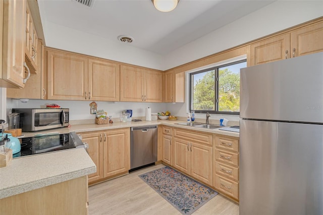 225 Cevera Dr, Dunedin, FL 34698 - kitchen featuring light brown cabinetry, light countertops, a sink, light wood-style floors, and appliances with stainless steel finishes