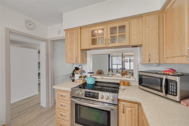 225 Cevera Dr, Dunedin, FL 34698 - kitchen featuring light wood finished floors, stainless steel appliances, light countertops, glass insert cabinets, and light brown cabinets
