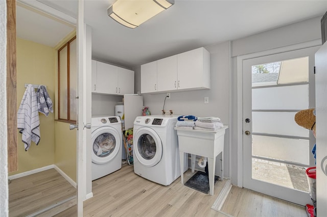 225 Cevera Dr, Dunedin, FL 34698 - washroom with washing machine and clothes dryer, light wood-style flooring, baseboards, and cabinet space