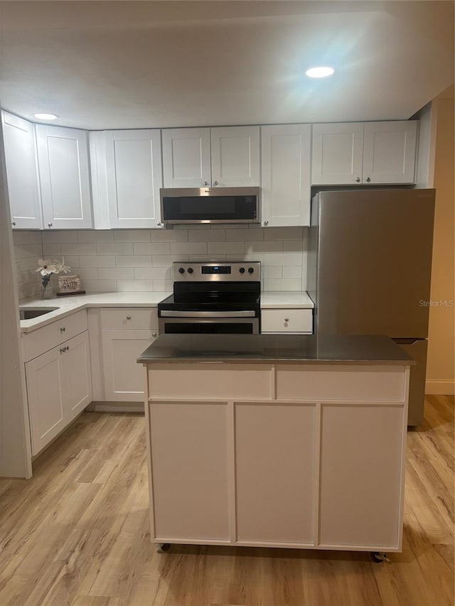 24862 US Highway 19 N Unit 2303, Clearwater, FL 33763 - kitchen featuring appliances with stainless steel finishes, decorative backsplash, white cabinets, and light wood-type flooring