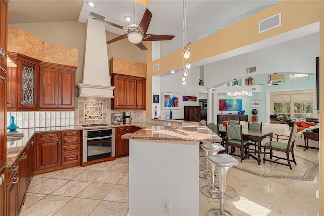 2613 59th St S, Gulfport, FL 33707 - kitchen featuring stainless steel appliances, ceiling fan, high vaulted ceiling, ornate columns, and a peninsula