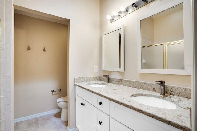 full bathroom with double vanity, a sink, a shower with door, and toilet
